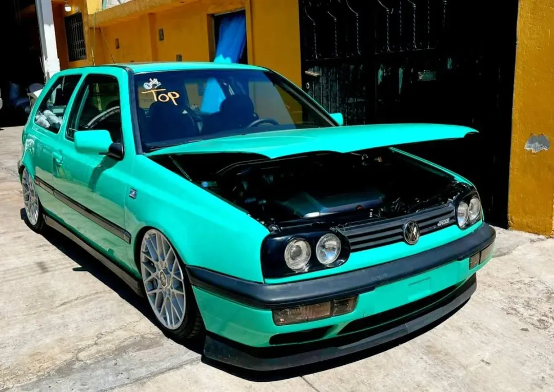 Golf MK3 verde con el cofre abierto mostrando el motor